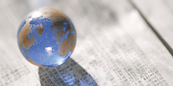 Small glass globe resting on financial newspaper pages