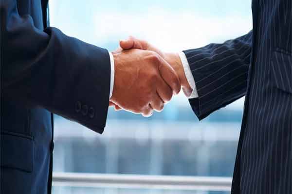 Two people in business suits shaking hands.