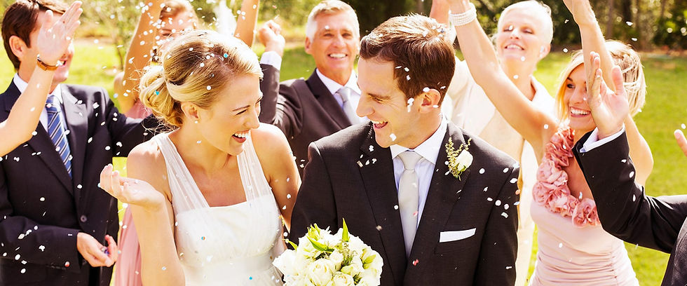 Smiling bride and groom celebrated with confetti by guests.