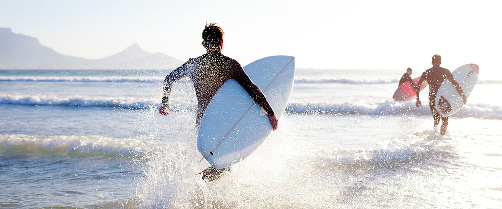 Surfers running into the ocean with surfboards
