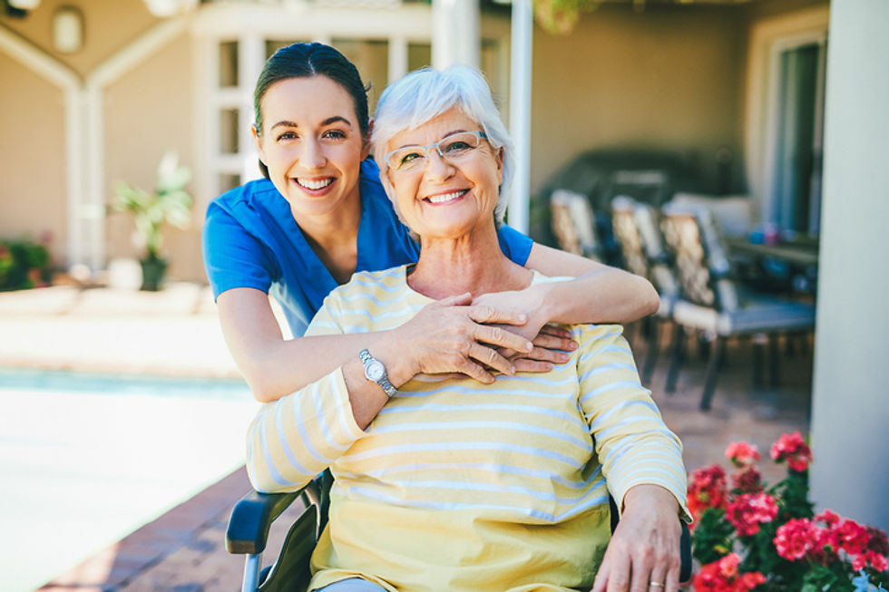 Caregiver hugging smiling senior woman outdoors