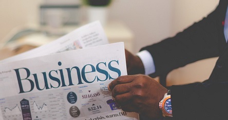 Person in a suit holding a Business newspaper