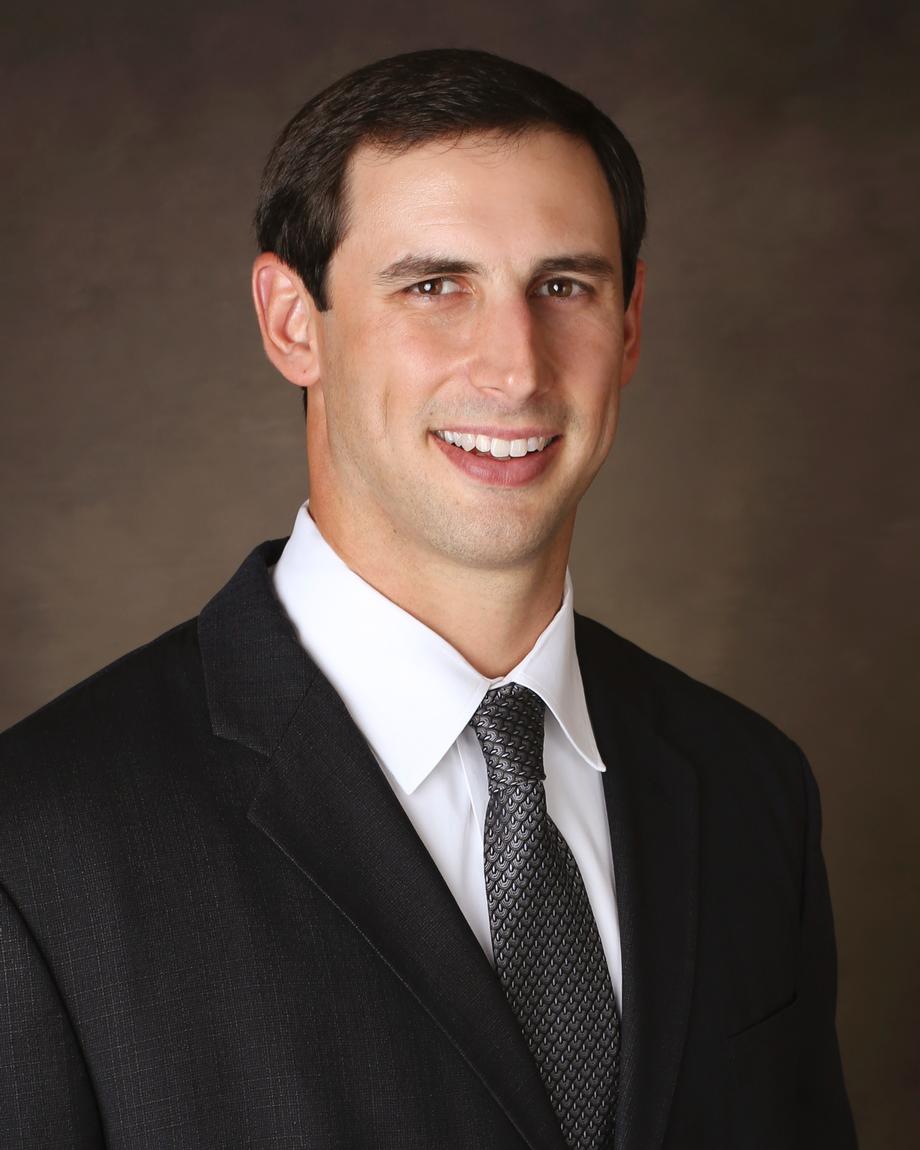 Professional headshot of a smiling man in a suit and tie.