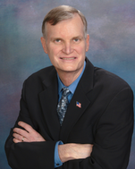 Man in black suit and blue tie with arms crossed