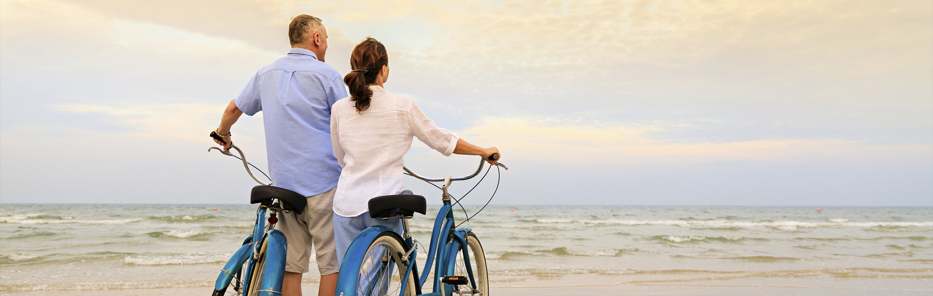 Woman with a blue bicycle looking at the ocean