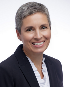 Smiling woman with short gray hair in a dark blazer