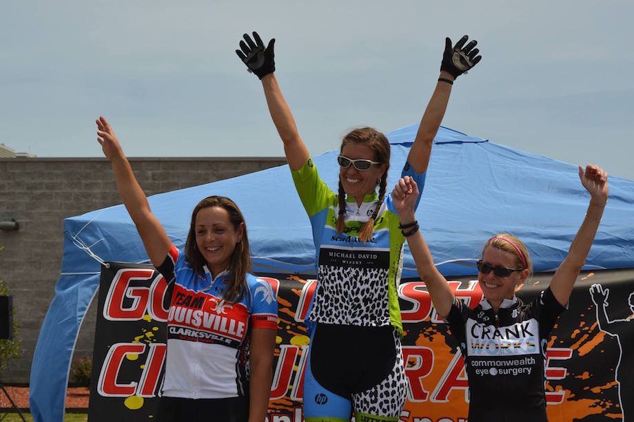 Three female cyclists celebrating on a community race podium.