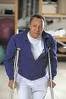 Man in a blue jacket using crutches to walk indoors.