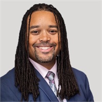Smiling professional man with locs in a suit and tie.