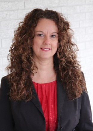 Woman with long curly hair in a black blazer and red top