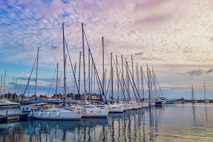 Sailboats moored in a marina under a sunset sky