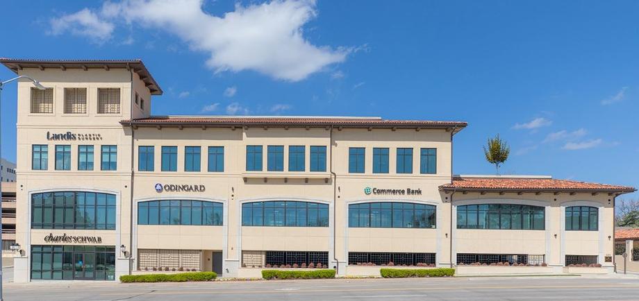 Modern commercial building with office storefronts under a blue sky.