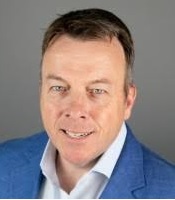 Associate in a blue blazer and white shirt smiling.