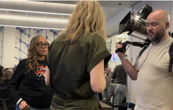 Cameraman filming woman being interviewed in a studio.