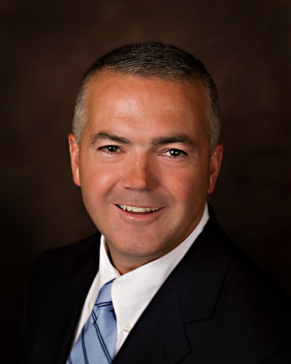 Professional headshot of a smiling man in a suit.