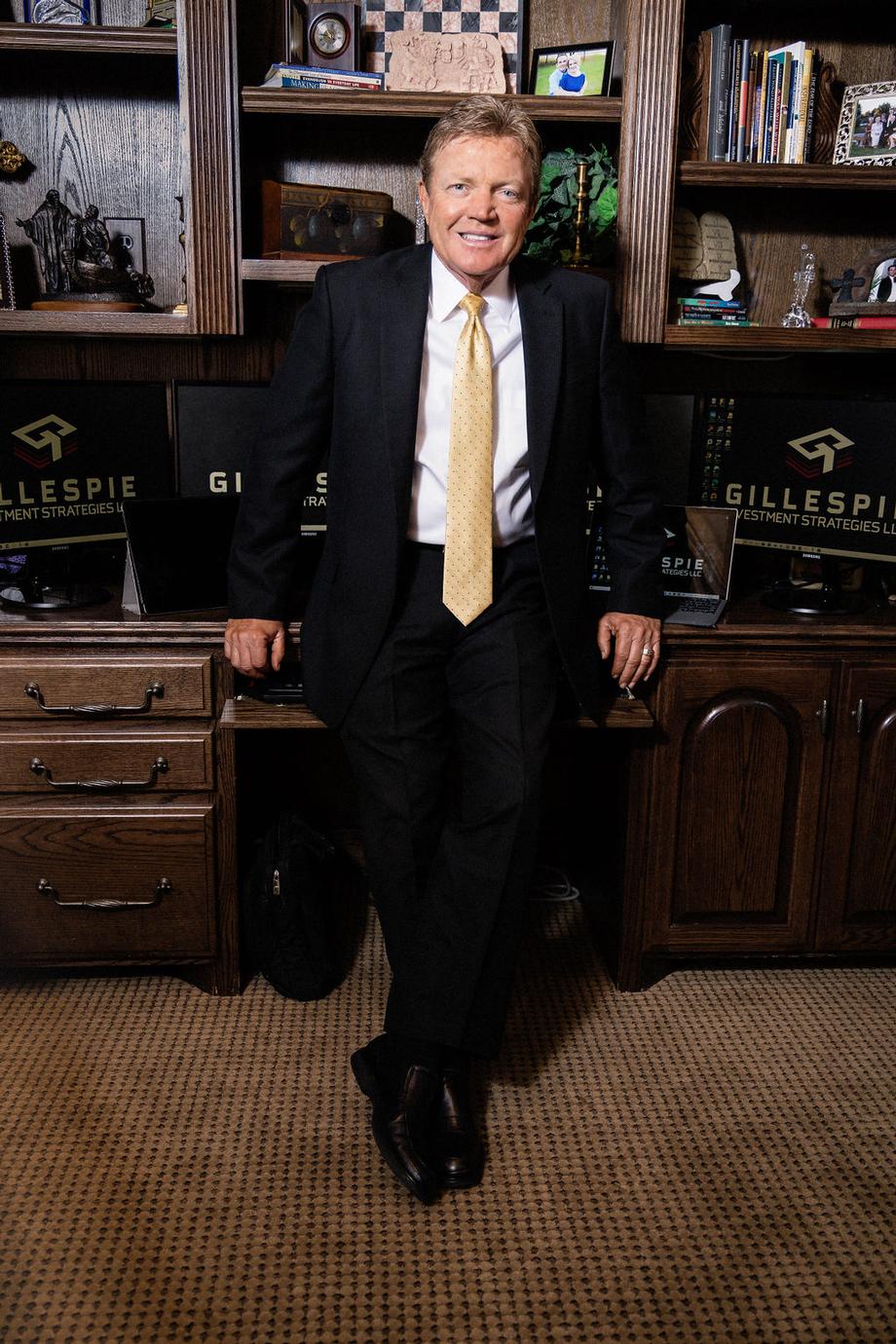 Smiling professional man in a suit leaning against a desk