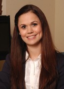 Smiling woman with long brown hair in a business suit.