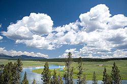 Winding river through green plains under a cloudy sky