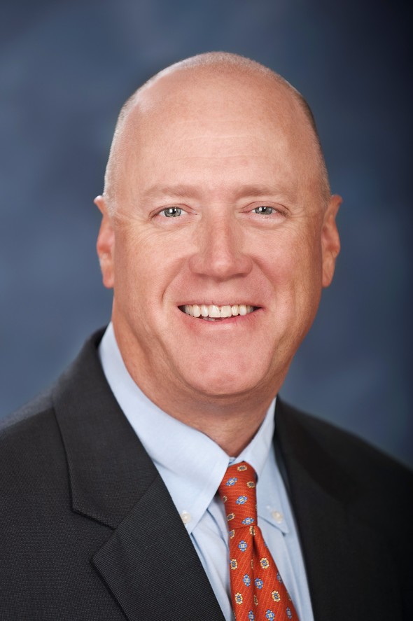Smiling bald man in a suit and red tie representing our team.