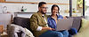 Smiling couple using a laptop together on a couch