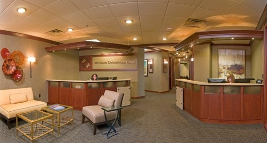 Modern office reception with seating and wood desks.