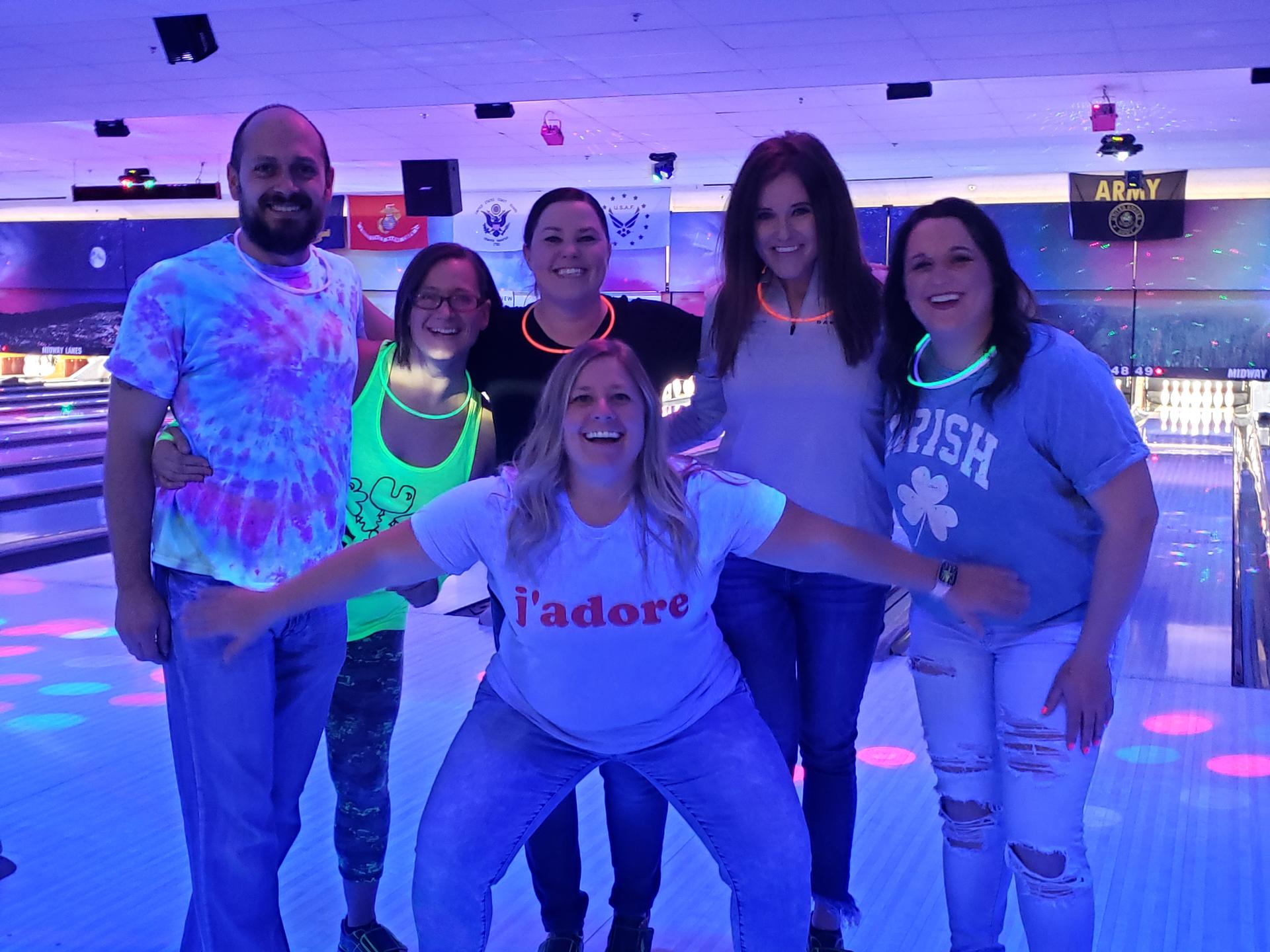 Friends smiling under neon lights at a bowling alley