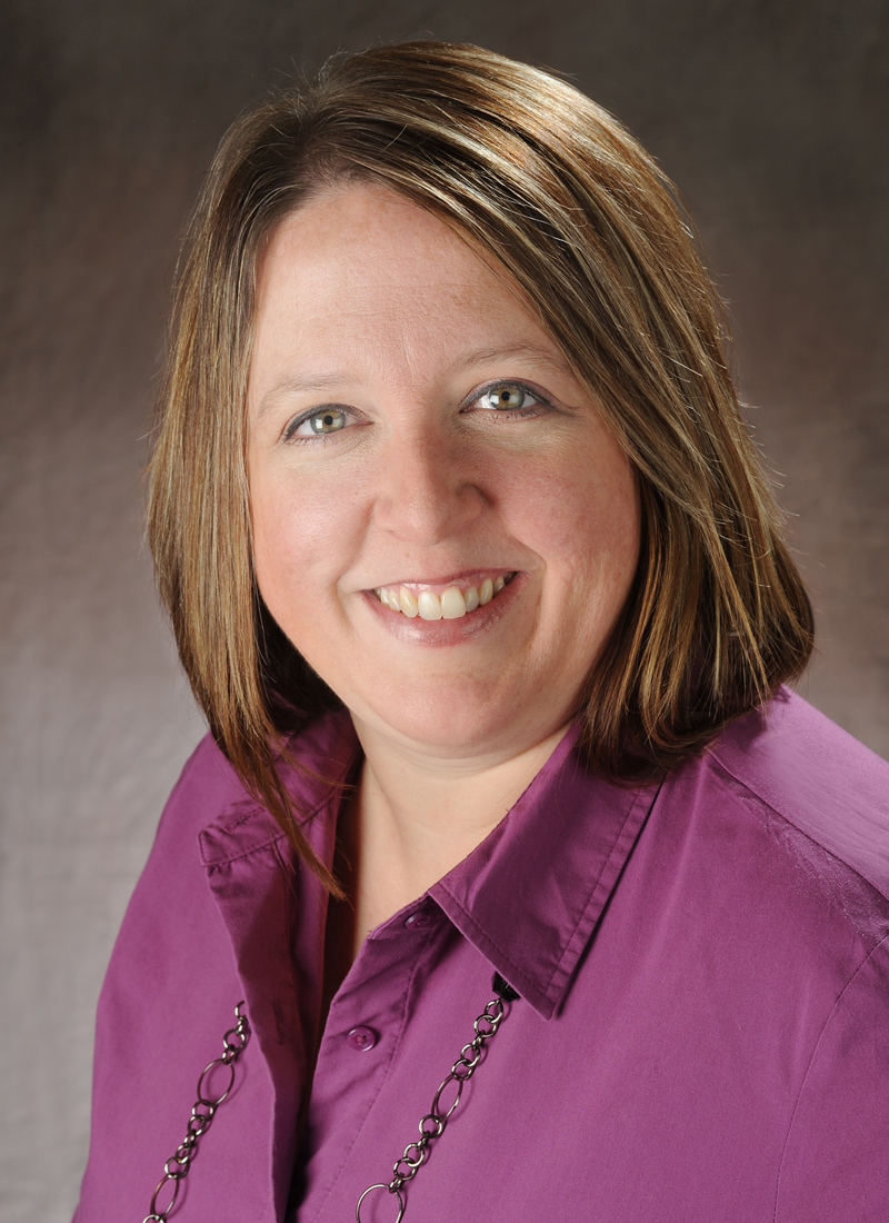 Smiling woman with brown hair wearing a purple shirt