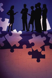 Professional silhouettes collaborating above puzzle pieces.