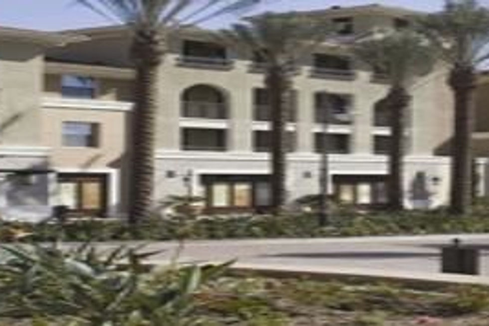 Modern multi-story apartment building with palm trees.