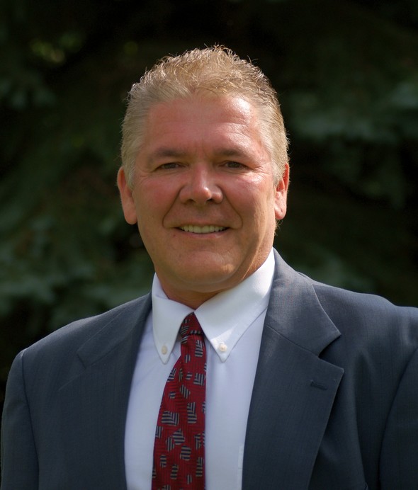 Professional headshot of a smiling man in a suit and tie.