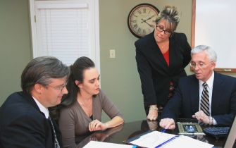 Four professionals discussing documents in a meeting.