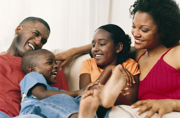 Smiling family of four laughing together on a sofa.