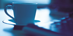Coffee cup on a saucer next to a laptop keyboard