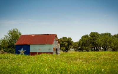 Barn painted like the Texas flag in a green field