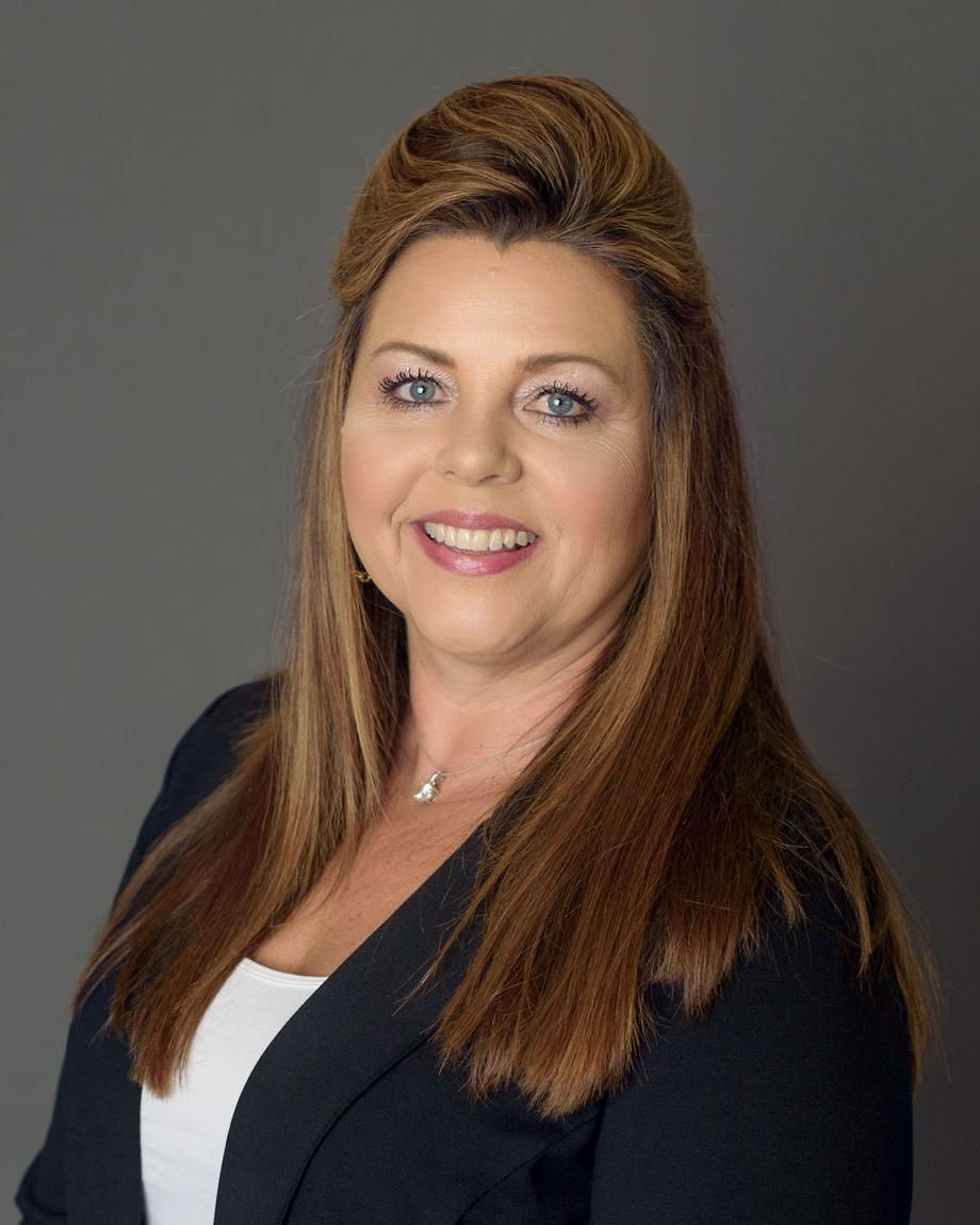 Smiling female staff member with long hair in a blazer.