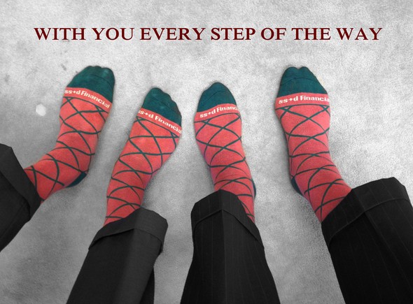 Two people wearing matching red patterned socks with the text 'With you every step of the way'