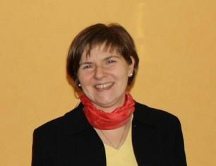 Smiling woman with short brown hair and a red scarf.