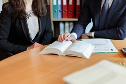 Two professionals reviewing a legal book in an office.