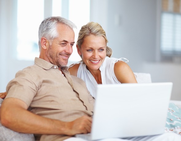 Smiling mature couple using a laptop together indoors