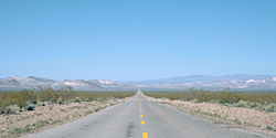 Long straight desert road leading to distant mountains