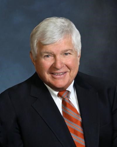 Smiling man with white hair wearing a suit and striped tie