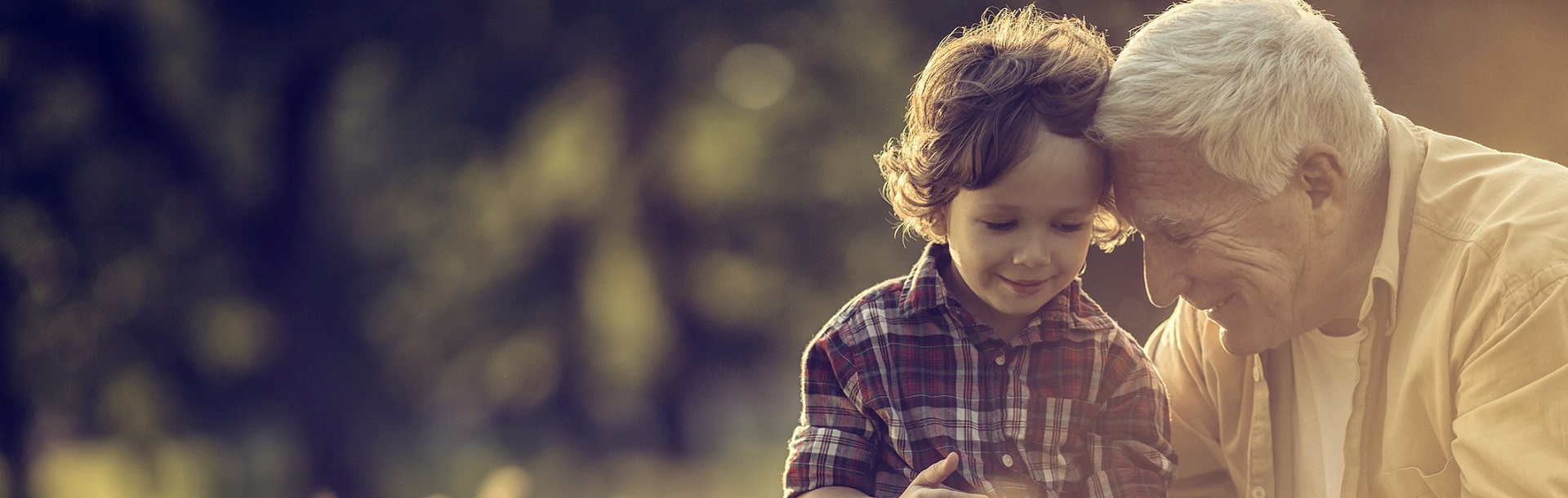 Smiling young boy with curly hair in a plaid shirt outdoors