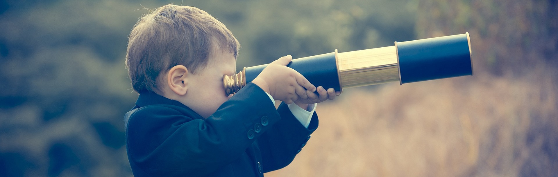 Young boy in a suit looking through a telescope