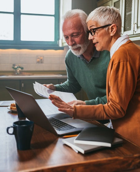 Senior couple reviewing documents on a laptop together.