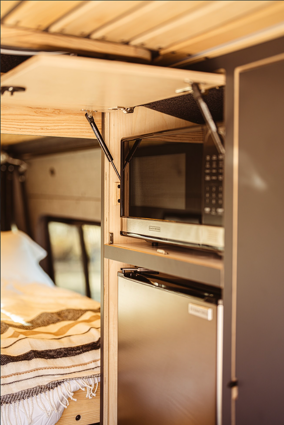 Inside a campervan featuring a microwave, fridge and more.