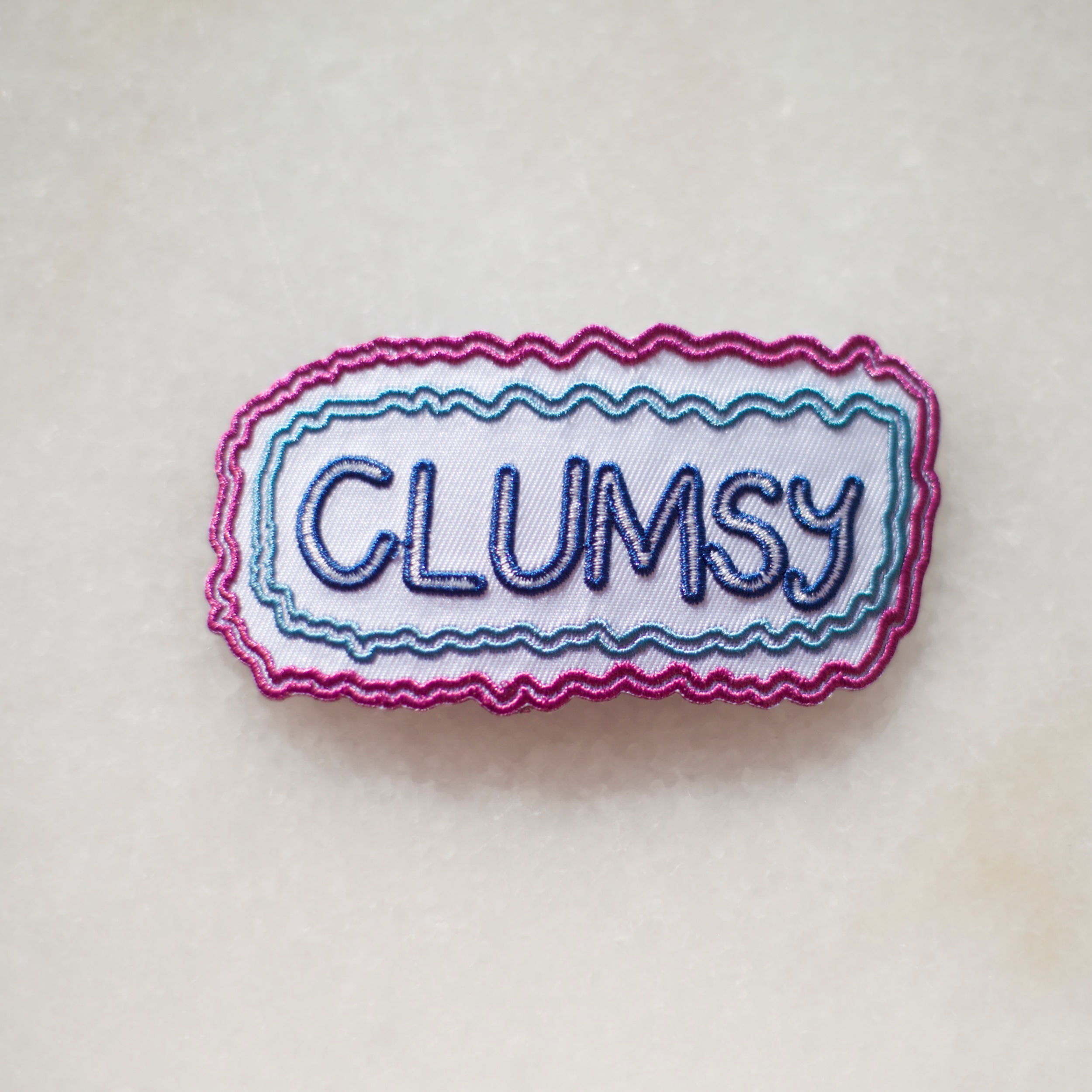Embroidered badge with the word 'clumsy'
