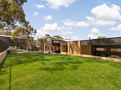 Modern home with light stone and dark cladding set against native bushland.
