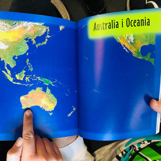 mapa Australii i Oceanii w książce oglądanej przez dzieci.