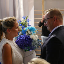 Nauczycielka wręcza bukiet kwiatów prezydentowi miasta.