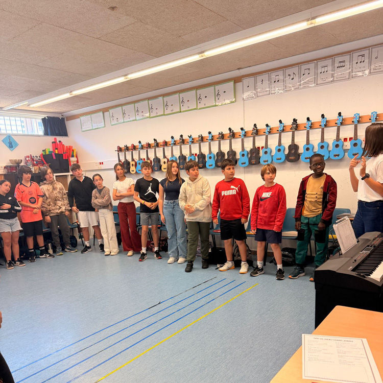 Zajęcia muzyczne w sali, gdzie na ścianie zawieszone są instrumenty.